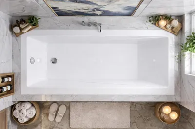A top-down view of a modern bathroom with a white bathtub as the central focus, surrounded by marble tiles and decorative elements.