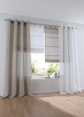 A window with multiple curtains and roman blinds, overlooking a garden.