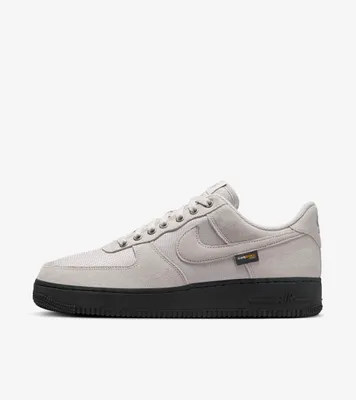 A side view of a Nike Air Force 1 '07 sneaker with a gray upper and a black sole.