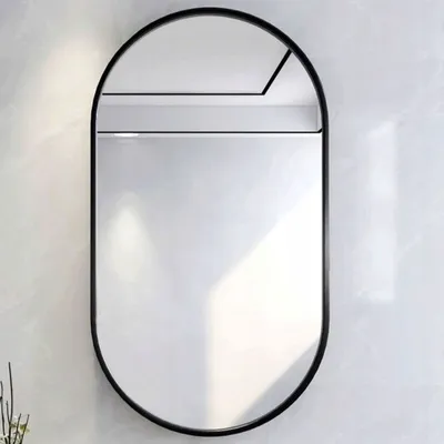 An oval mirror with a black frame mounted on a textured wall.