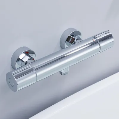 A close-up shot of a chrome shower mixer tap mounted on a light gray wall, with a white surface in the foreground.