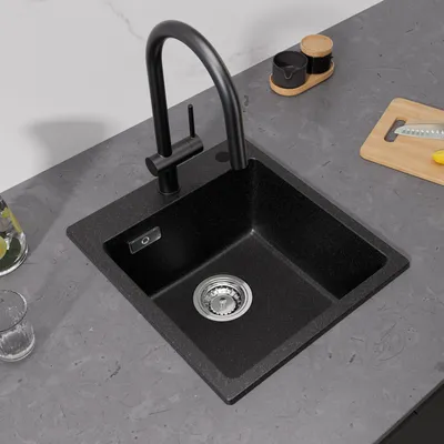 A black granite kitchen sink with a black faucet is shown on a gray countertop.