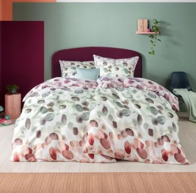 A bedroom scene with a bed made with the featured bedding.