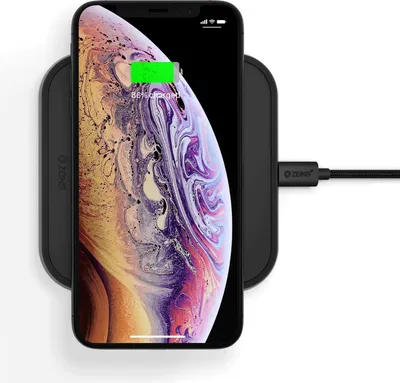 A smartphone is placed on a wireless charging pad, which is connected to a power source via a USB-C cable.