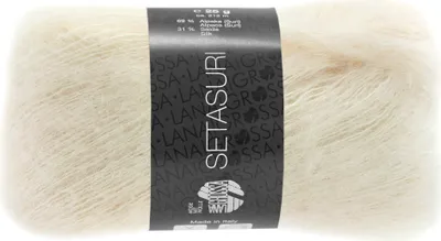A ball of cream-colored yarn with a black label wrapped around it.