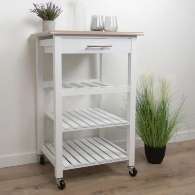 A white kitchen trolley with a wooden top, featuring shelves and a drawer, placed against a white wall.