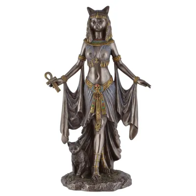 A bronze-colored statue of the Egyptian goddess Bastet, depicted with a cat's head, standing with a small cat at her feet.