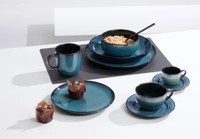 A table setting with a breakfast set, including plates, bowls, cups, and muffins.