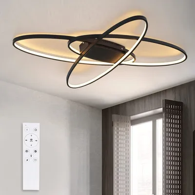 A modern black LED ceiling light with a remote control on a white wall.