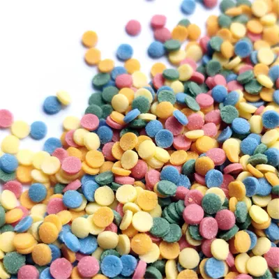 A close-up shot of colorful sprinkles scattered on a white surface.