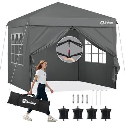A woman is carrying a bag with a tent inside, with the tent set up in the background. Accessories for the tent are laid out in the foreground.