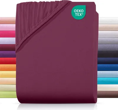 A folded burgundy fitted sheet is shown, with a stack of other colored sheets visible in the background.
