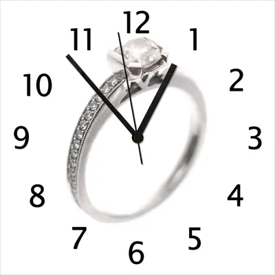 Produktbild von Wallario Design Wanduhr Silberner Verlobungsring in Nahaufnahme mit Fokussierung aus Echtglas, Größe 30 x 30 cm