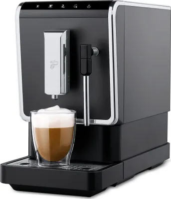 A black and silver Tchibo coffee machine with a glass of coffee in front of it.
