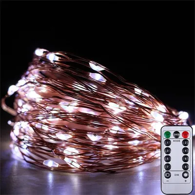 A coiled string of white LED lights with a copper wire, next to a remote control.