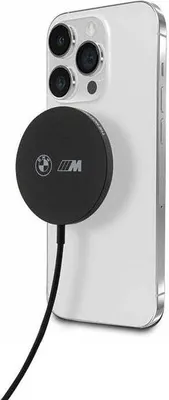 A white iPhone with a black inductive charger attached to the back, featuring the BMW M logo.