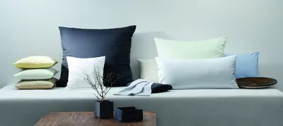 A collection of pillows and a folded blanket arranged on a sofa or bench.