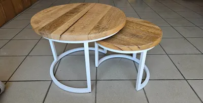 Two round nesting coffee tables with wooden tops and white metal bases are shown on a tiled floor.