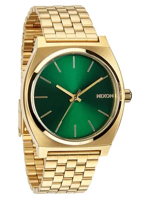 A close-up studio shot of a gold Nixon Time Teller watch with a green dial.
