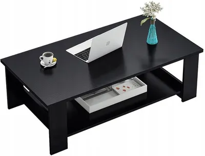 A black coffee table with a laptop, a cup of coffee, and a vase of flowers on it.