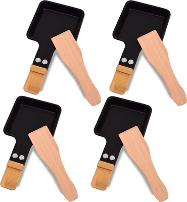 Four raclette pans with wooden spatulas arranged on a white background.