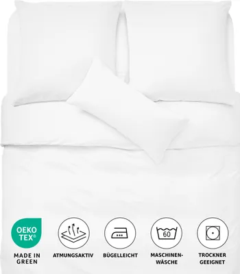 A white bedding set with pillows laid out flat, accompanied by several icons and text indicating product features and care instructions.