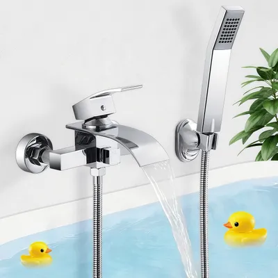 A modern bathroom faucet with a waterfall spout and a handheld showerhead is mounted on a white wall above a bathtub filled with blue water. Two yellow rubber ducks float in the water.