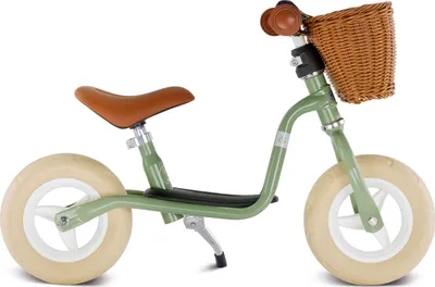 A green balance bike with a brown seat and handlebars, and a wicker basket on the front.