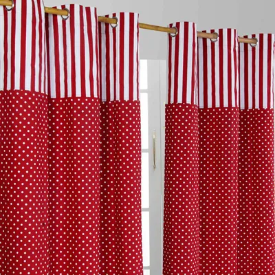 A close-up view of red and white striped and polka dot curtains hanging on a wooden rod.