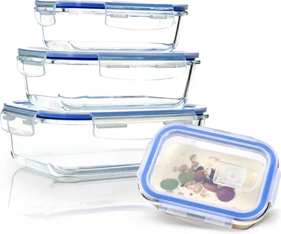 A stack of glass food storage containers with blue lids, with one container in the foreground containing food.
