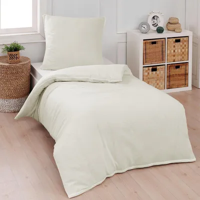 A neatly made bed with cream-colored bedding in a bedroom setting.