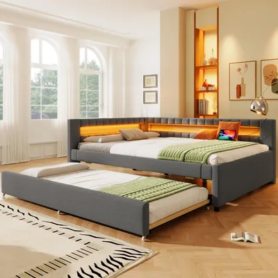 A modern bedroom with a grey upholstered bed frame featuring integrated LED lighting and a pull-out trundle bed.