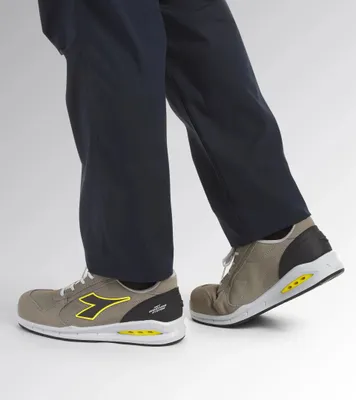 A person wearing dark blue pants and gray work shoes.