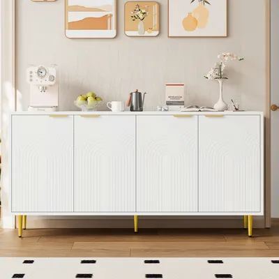 A white sideboard with gold legs and handles, decorated with arched patterns on the doors, is displayed in a room with artwork on the wall and a rug on the floor.