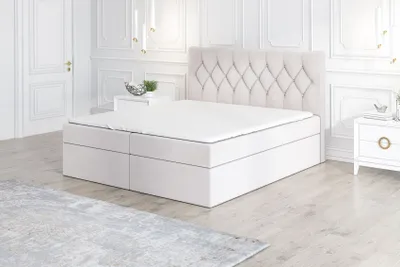 A white boxspring bed with a tufted headboard is shown in a well-lit, minimalist bedroom setting.