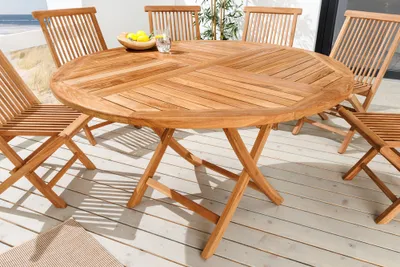 A round teak garden table with chairs set up on a wooden deck.