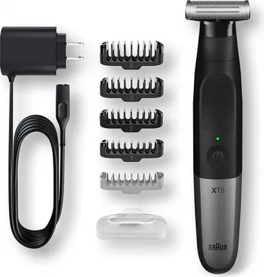 A set of grooming tools including a shaver, charging cable, and multiple trimming attachments, neatly arranged on a white background.
