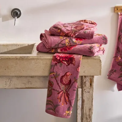 A stack of floral-patterned towels on a stone counter next to a sink.