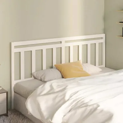 A white wooden headboard is shown on a bed with white bedding and a yellow pillow.
