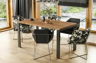 A dining table and chairs set in a well-lit room with large windows overlooking a garden.