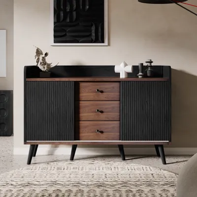 A modern sideboard with fluted doors and drawers, decorated with sculptures and artwork, in a well-lit room.