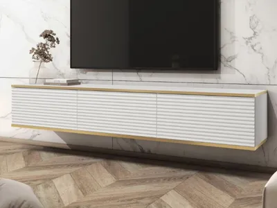 A modern white TV cabinet with gold trim mounted on a marble wall.