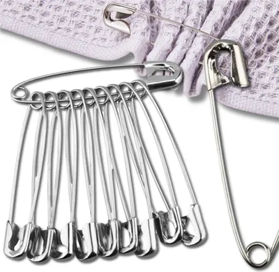 A group of safety pins are arranged on a textured fabric.