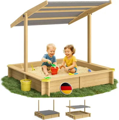 Two children playing in a wooden sandbox with a canopy.