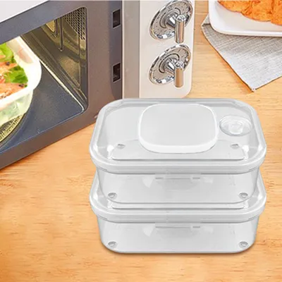 A stack of three clear plastic food storage containers with white lids sits on a wooden surface, next to a microwave.