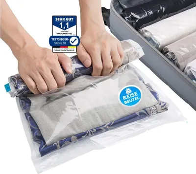 Hands are shown rolling up clothes into a vacuum seal bag, with a suitcase in the background filled with similar rolled items.