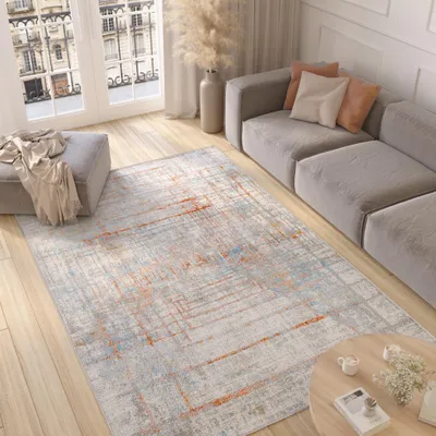 A modern living room with a sofa, rug, ottoman, and coffee table.