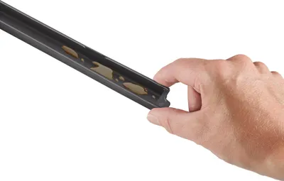 A hand holding a black vacuum sealer accessory with some liquid inside.
