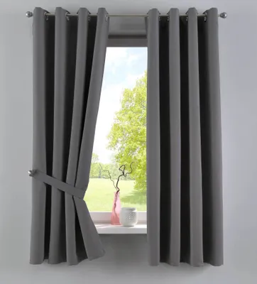 A dark gray curtain is tied back with a fabric strap, revealing a window with a view of trees and a green field. A pink vase and a white pot sit on the windowsill.