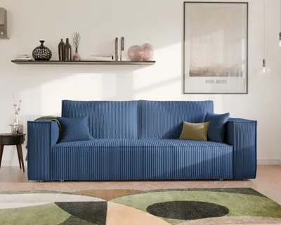 A modern living room with a blue sofa, a shelf with decorative items, and a framed picture on the wall.